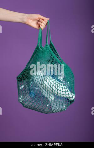 https://l450v.alamy.com/450v/2hmpeka/womans-hand-holds-a-green-mesh-bag-with-plastic-bottles-on-a-purple-background-the-concept-of-sorting-and-recycling-garbage-2hmpeka.jpg