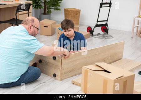 Father tries on the furniture boards to see if they fit together. Stock Photo