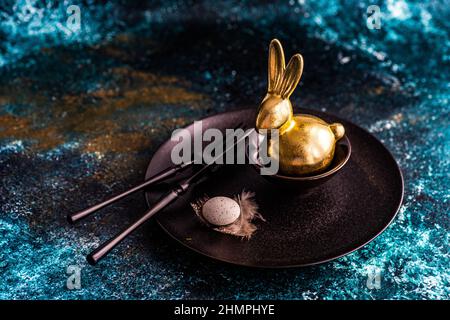 Easter place setting on a table with a golden Easter bunny and Easter egg Stock Photo