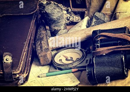Geological fieldwork tools: map case, geological hammer, compass, binoculars, storm jacket, drill core, rock samples, topographic maps Stock Photo