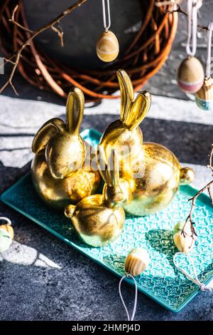 Festive golden Easter bunny decorations on a table with Easter eggs Stock Photo