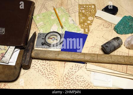 Geological fieldwork tools: map case, geological hammer, compass, magnifying glass, drill core, rock samples, topographic and geological maps Stock Photo