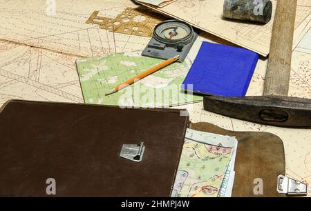 Geological fieldwork tools: map case, geological hammer, compass, magnifying glass, drill core, rock samples, topographic and geological maps Stock Photo