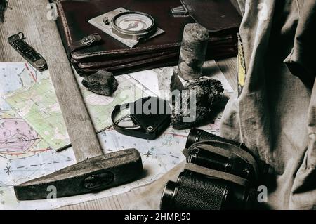 Geological fieldwork tools:map case, geological hammer, compass, magnifying glass, pocket knife, binoculars, storm jacket, drill core, rock samples, t Stock Photo
