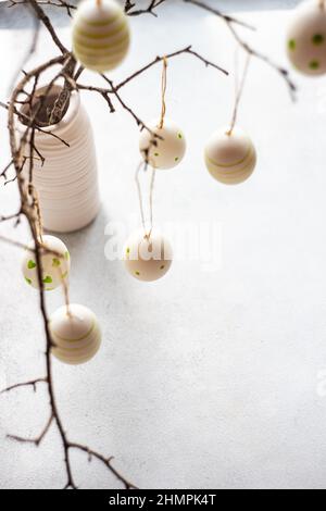 Painted Easter egg decorations hanging on branches in a vase Stock Photo