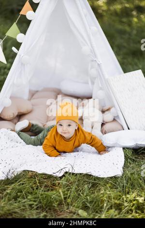 One year old baby boy dressed in stylish outfit posing inside colorful teepee tent among green summer nature. Concept of childhood picnic and free time Stock Photo Alamy