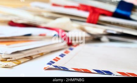 Old letters on table , in the foreground an opened airmail envelope , in the background stacks of letters  lay one above the other ,clean up and memor Stock Photo