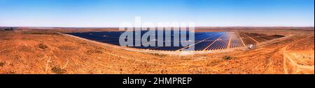 Massive solar power generation plant with solar panels on red soil of Australian outback at Broken HIll city in aerial panorama. Stock Photo