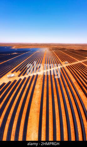 Vertical lines of solar panel elements at Broken Hill solar plant on red soil in Australian outback - aerial view. Stock Photo