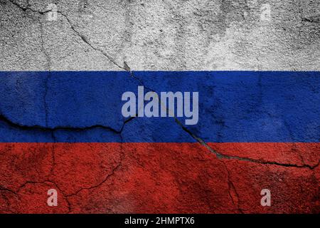Full frame photo of a weathered flag of Russia painted on a cracked wall. Stock Photo