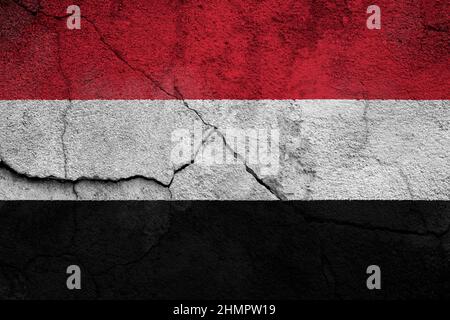 Full frame photo of a weathered flag of Yemen painted on a cracked wall. Stock Photo