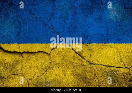 Full frame photo of a weathered flag of Ukraine painted on a cracked wall. Stock Photo