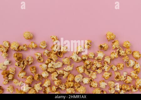 frame of caramel popcorn and empty space for text on pink background, sweet snacks Stock Photo