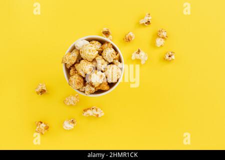 caramel popcorn in bowl on yellow with copy space for text, close up, sweet snacks, caramel popcorn for watching movies, top view Stock Photo