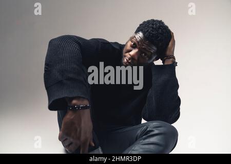 black man seated scratching his head staring at the camera white background - medium shot. High-quality photo Stock Photo