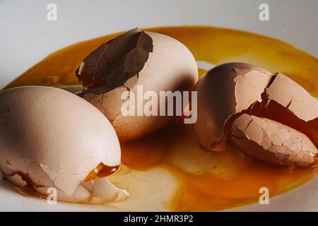 Cracked eggs on white plate with morning light. Brocken eggshell  Stock Photo
