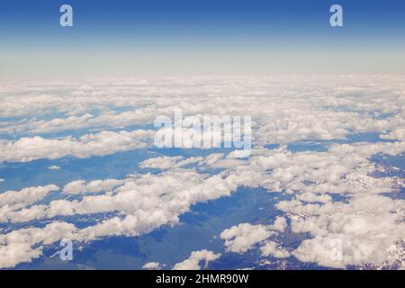 Fluffy clouds and blue sky from above the clouds, viewed from an airplane. Stock Photo