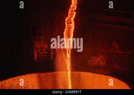 A stream of molten slag is poured into a metallurgical ladle Stock Photo