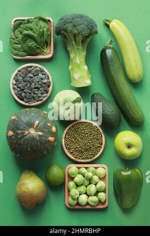 Green fruits and vegetables on a green background. Spinach, pumpkin seeds, mung bean, pumpkin, pear, lime, broccoli, Brussels sprouts, kohlrabi, zucch Stock Photo