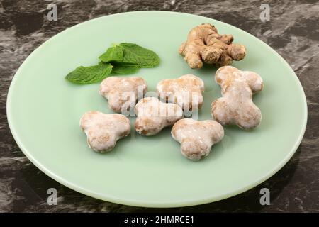 Glazed mint gingerbread cookies with ginger root and fresh mint leaves on light green plate Stock Photo