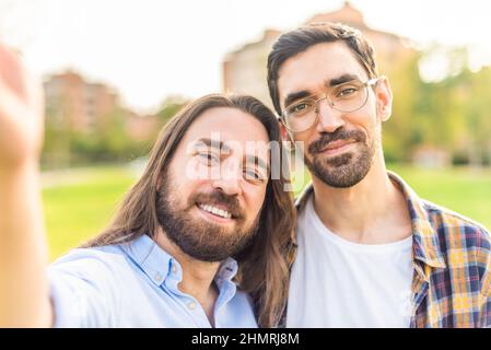 happy gay couple taking a selfie in the park Stock Photo