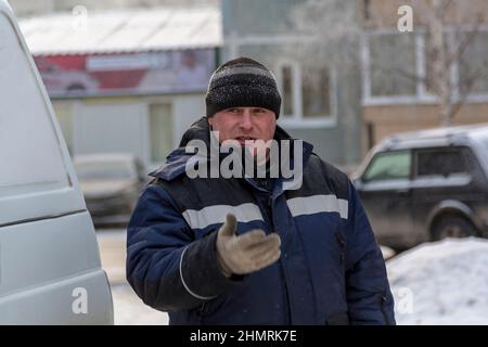 Close-up of a worker in a blue jacket and a knitted hat at the workplace Stock Photo