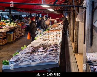 Venice, Italy - January 5 2022: Customers Shopping at Rialto Fish Market or Mercato del Pesce al Minuto at Rialto in Venice with Covid Restrictions. Stock Photo