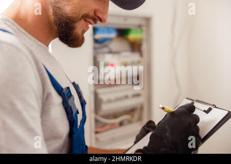 Closeup of electrician writing on a clipboard the data collected on a residential electric panel Stock Photo