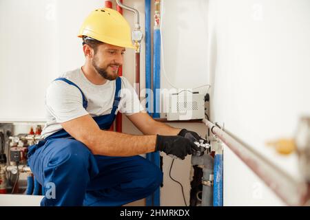 Cheerful male worker, plumber checking pipes while installing heating system in apartment Stock Photo