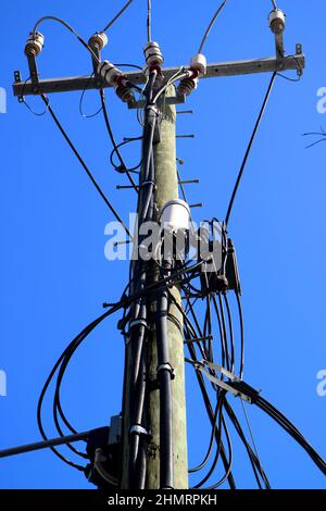 Up angle shot of an old wooden telephone and power line pole against blue sky in Australia Stock Photo
