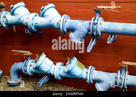 Close up of light blue water pipes against red brick background Stock Photo