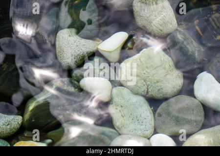 looking at the pebble stones in the water through wobbling surface Stock Photo