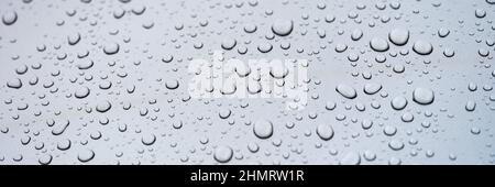 Raindrops on glass against gray sky closeup Stock Photo