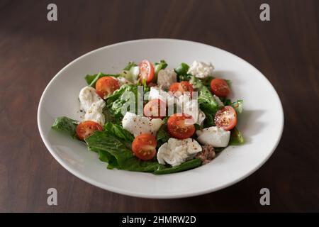 Salad with canned tuna, mozzarella and tomatoes in white bowl, shallow focus Stock Photo