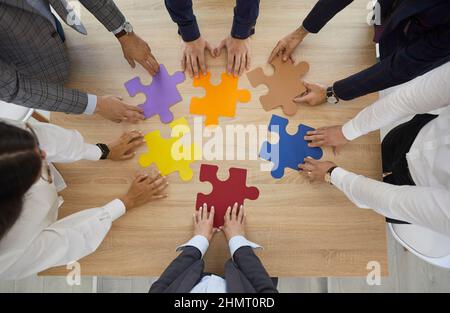 Employees connect jigsaw puzzles involved in teambuilding Stock Photo