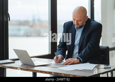 Focused mature businessman in suit signs documents, puts signature on contract  Stock Photo