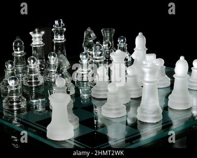 Chess set with glass material reflected. White pieces and transparent resin material reflected in the glass chess board. Black backgroud. Close up. Stock Photo