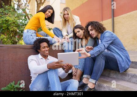 Company of diverse friends watching video on tablet Stock Photo