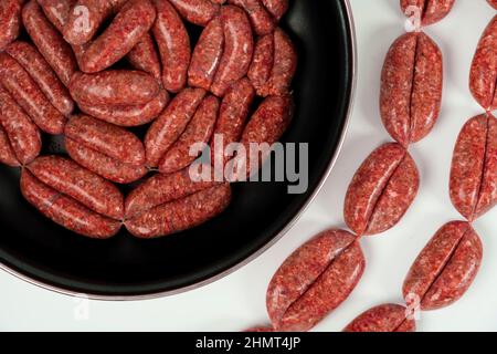 Raw homemade sausages close-up isolate in a cooking pan on a white background Stock Photo