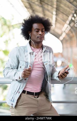 Portrait of African American man with casual clothes and afro hairstyle listening to music and dancing. People lifestyle concept. Stock Photo