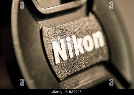 Nikon frontlens cover. Foregroung and backround blurred. Focus on the i letter. Texture of the plastic surface visualized as sunlight is reflected. Stock Photo