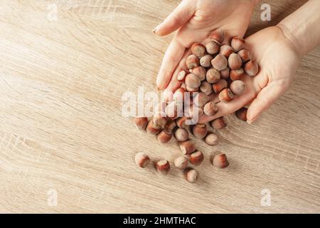 shelled hazelnuts in hands on a wooden background Stock Photo