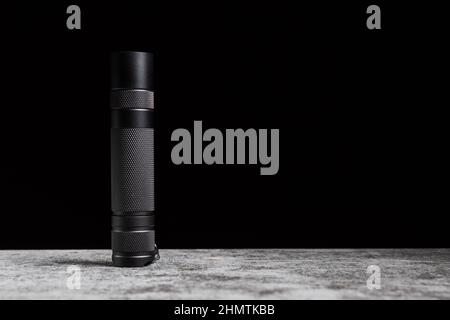 Flashlight stands on a table on a black background with copy space. Stock Photo