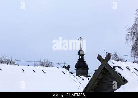 Old wooden church made of round logs. Cross on the dome. Winter Russian landscape. Snow covered trees. Abandoned old Russian village covered with snow Stock Photo