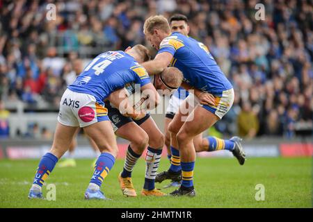 Leeds, UK. 12 February 2022 - Oliver Holmes of Warrington Wolves tackled by Brad Dwyer (14) of Leeds Rhinos during the Rugby League Betfred Super League Round 1 Leeds Rhinos vs Warrington Wolves at Emerald Headingley Stadium, Leeds, UK  Dean Williams Credit: Dean Williams/Alamy Live News Stock Photo