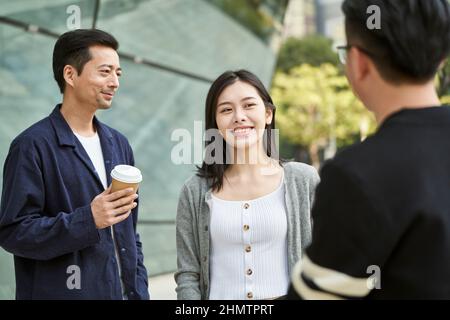 young asian people standing talking on street happy and smiling Stock Photo