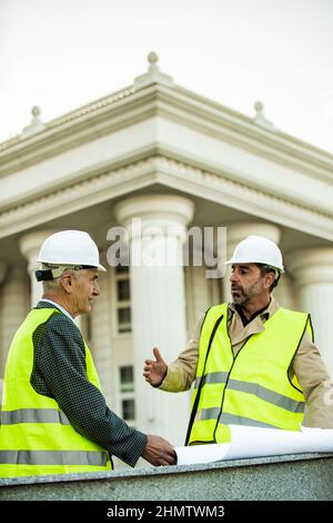 Two senior construction workers are having a conversation about the new plans Stock Photo
