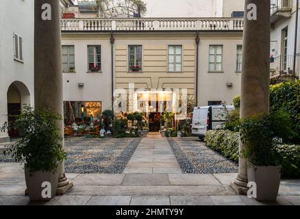 A flower shop with many potted plants displayed on the front in the courtyard of an old palace in the historic centre of Turin, Piedmont, Italy Stock Photo