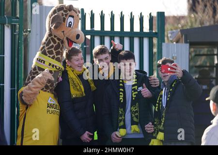 Sutton United fans pose for a picture with Jimmy the Giraffe mascot before the Sky Bet League Two match at the VBS Community Stadium, London. Picture date: Saturday February 12, 2022. Stock Photo