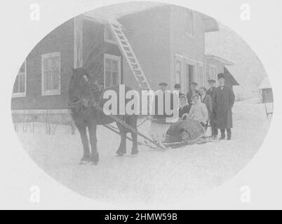 Authentic vintage photograph of small group of people sitting on and standing behind a horse drawn sledge in front of wooden house, Sweden Stock Photo